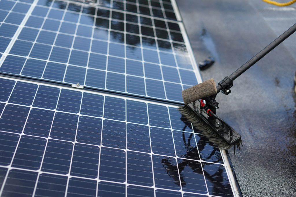 Cleaning solar panels with a long handled brush.